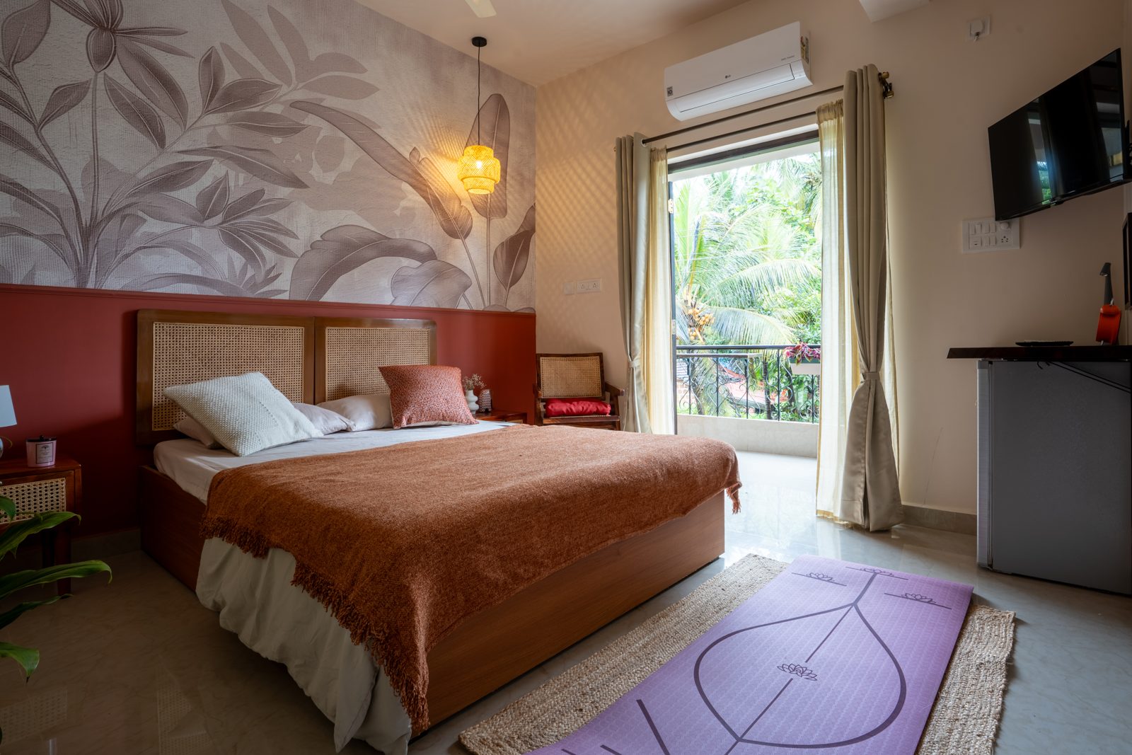 Bedroom with terracotta bedspread, rattan headboard, and balcony overlooking palm trees at Trendy Terracotta Nest